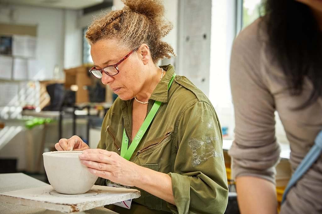 Women working in glass studio crafting dish