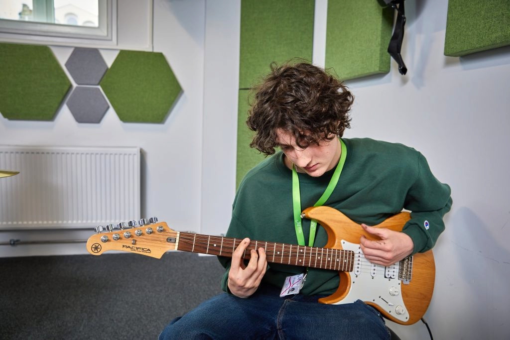 Young white male playing guitar in music studio