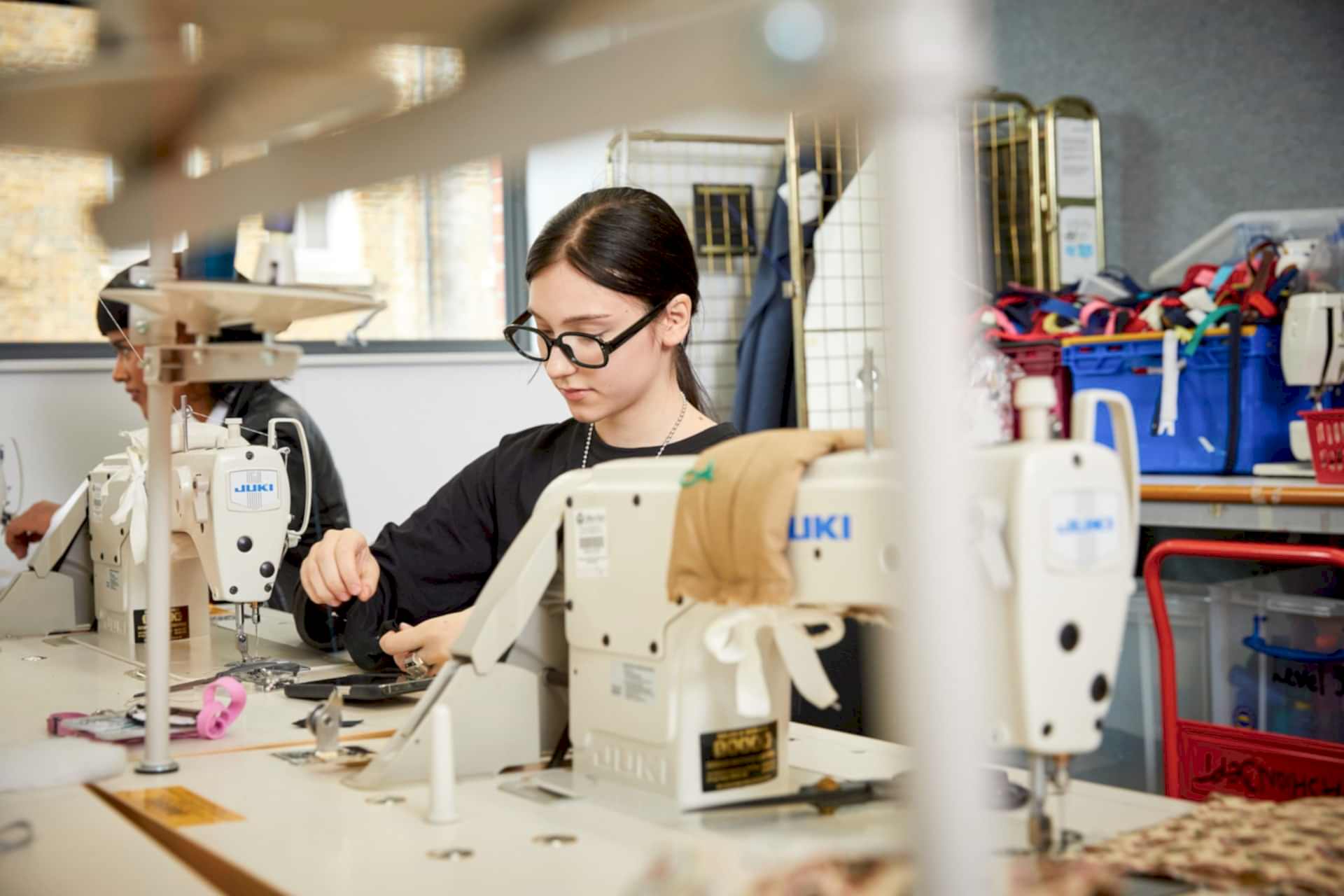 Young female student working at sewing machine in fashion studio.
