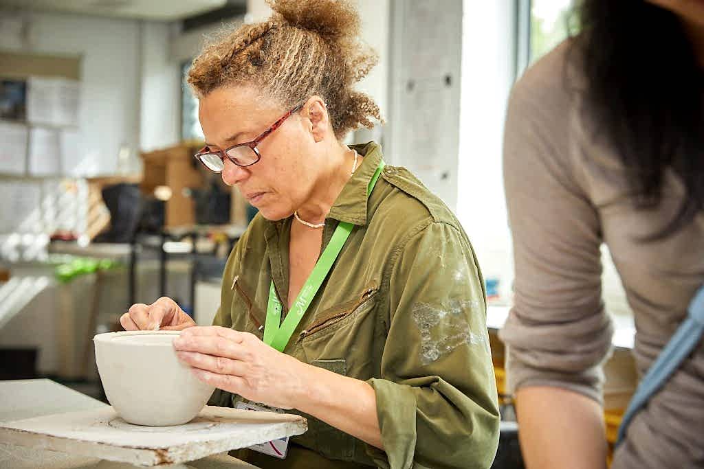 Women working in glass studio crafting dish