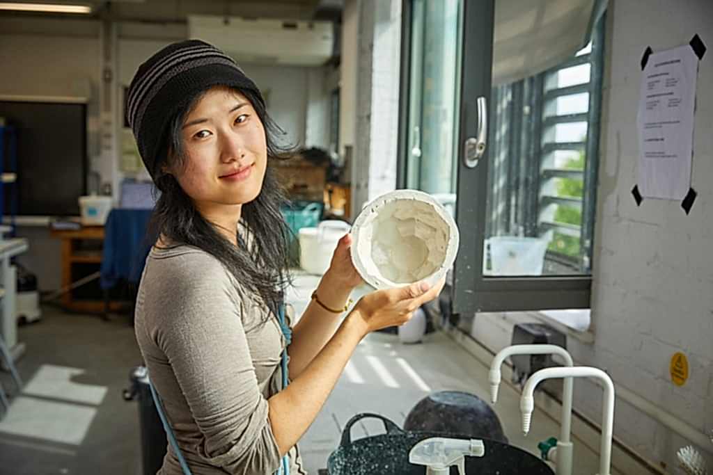 Young Asian women holding glasswork in hands as she looks at camera